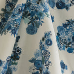 Draped fabric yardage in a painterly floral print in shades of blue and navy on a cream field.