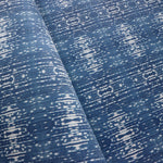 Close up of printed grasscloth with ikat stripe design in blue and cream 