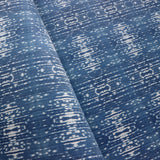 Close up of printed grasscloth with ikat stripe design in blue and cream 