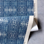 Draped yardage of printed grasscloth with ikat stripe design in blue and cream 