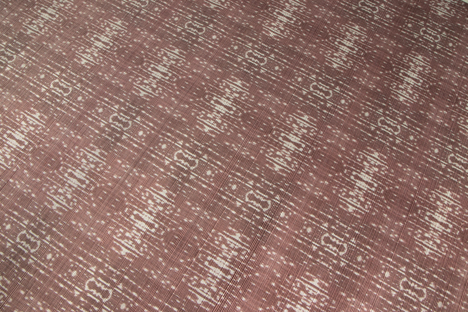 Close up of printed grasscloth with ikat stripe design in mauve red and cream 