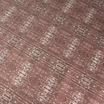 Close up of printed grasscloth with ikat stripe design in mauve red and cream 