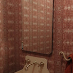Powder room setting with printed grasscloth with ikat stripe design in mauve red and cream 