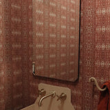 Powder room setting with printed grasscloth with ikat stripe design in mauve red and cream 