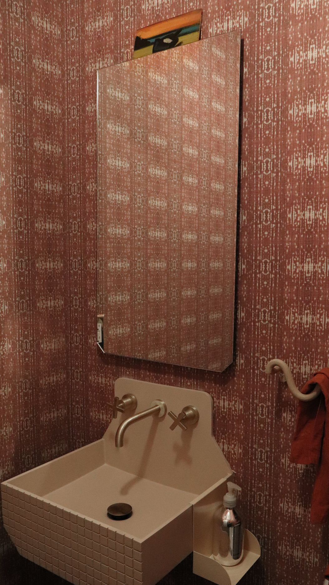 Powder room setting with printed grasscloth with ikat stripe design in mauve red and cream 