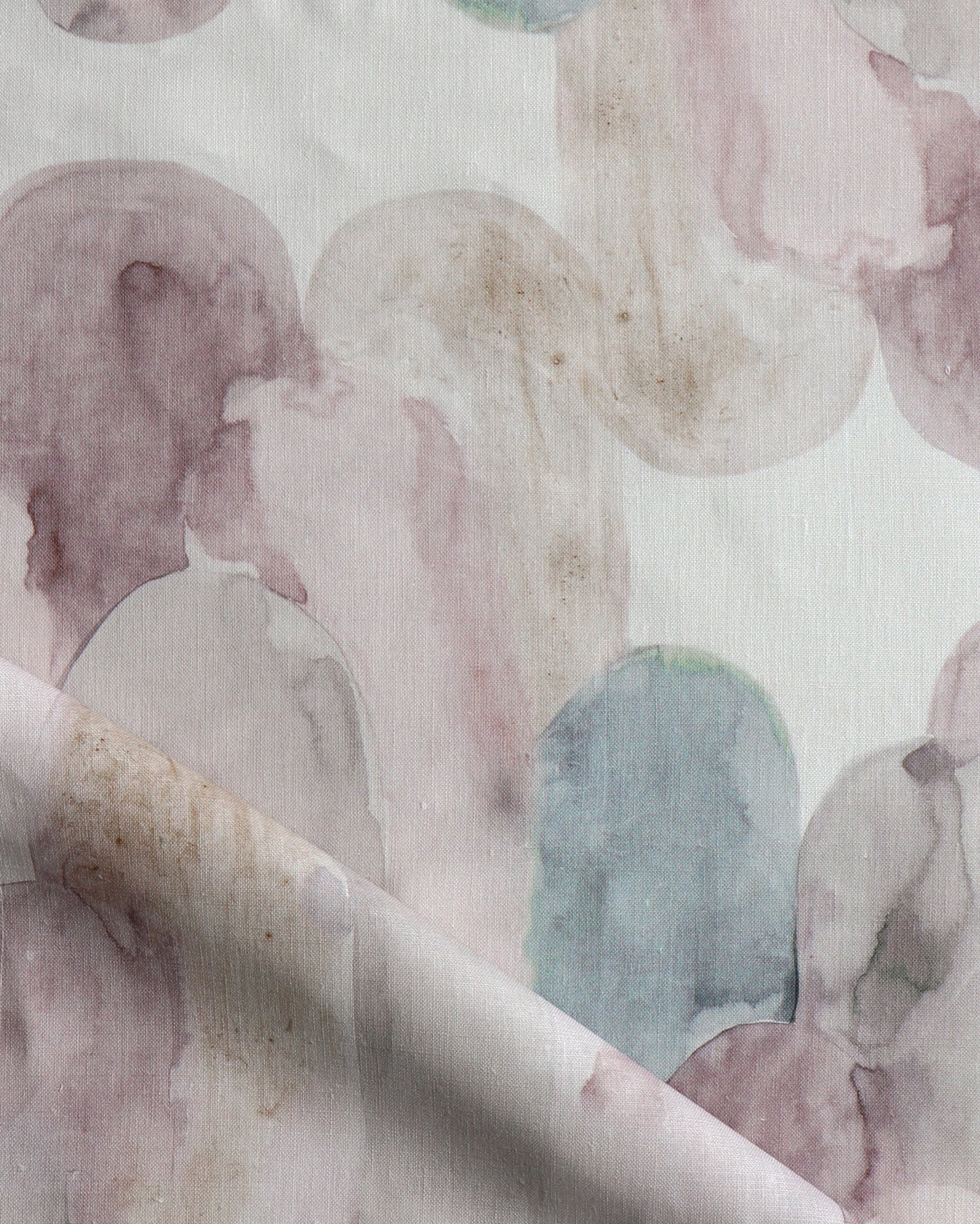 Detail of draped fabric in watercolor elongated pill pattern in soft purple, tan and teal on a white field.