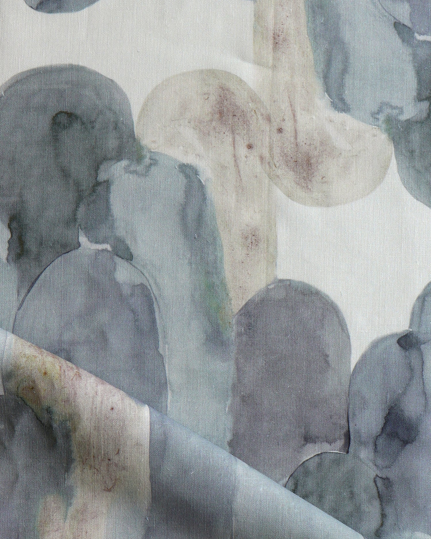 Detail of draped fabric in watercolor elongated pill pattern in moody blues and taupe on a white field.