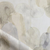 Detail of draped fabric in watercolor elongated pill pattern in soft beige and taupe on a white field.