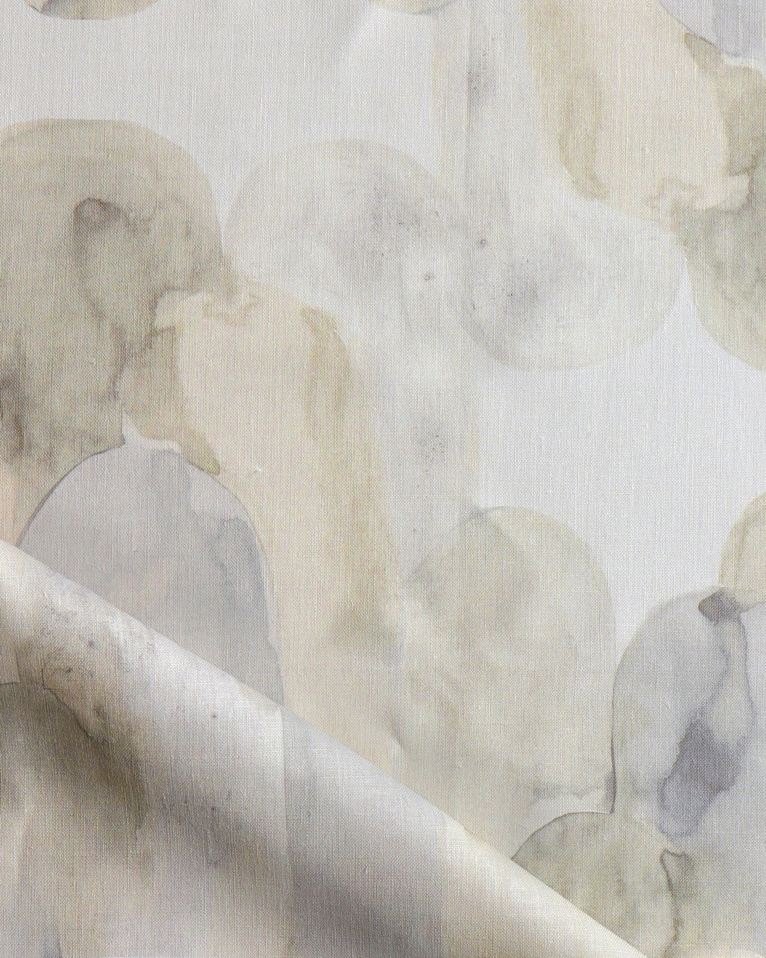 Detail of draped fabric in watercolor elongated pill pattern in soft beige and taupe on a white field.