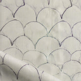 Detail of draped fabric in a watercolor linear scallop pattern in navy on a cream field. 