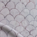 Detail of draped fabric in a watercolor linear scallop pattern in purple on a lilac field. 
