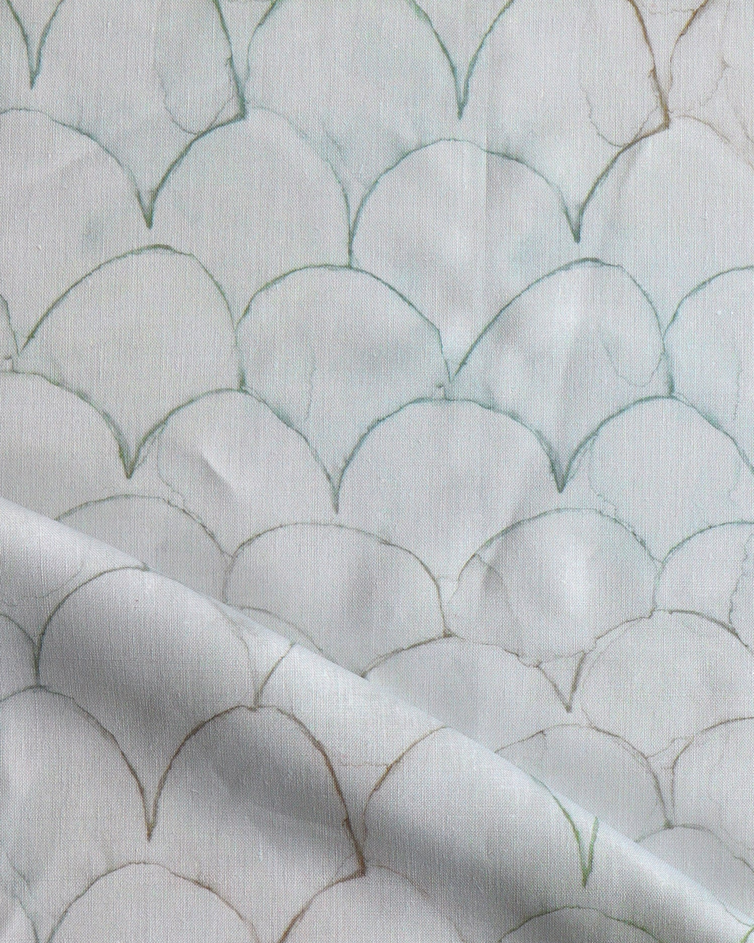 Detail of draped fabric in a watercolor linear scallop pattern in green on a sage field. 