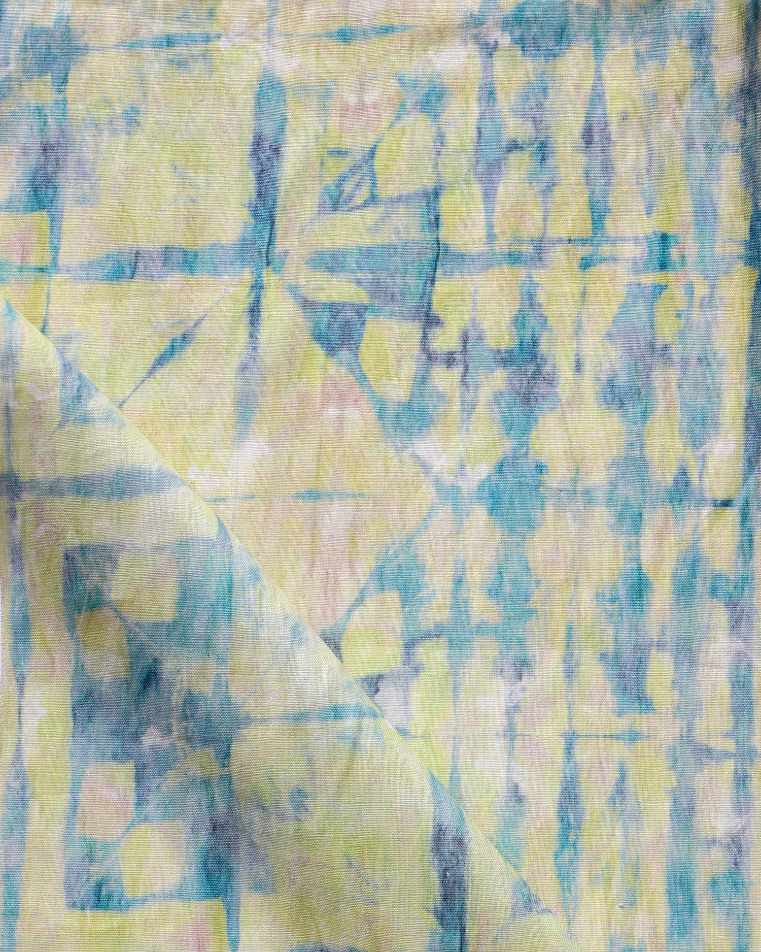 Detail of draped fabric in a watercolor dyed grid print in mottled yellow, blue and white.