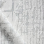 Detail of draped fabric in a watercolor dyed grid print in mottled white and gray.