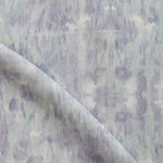 Detail of draped fabric in a watercolor dyed grid print in mottled purple and turquoise.