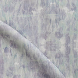 Detail of draped fabric in a watercolor dyed grid print in mottled purple and turquoise.