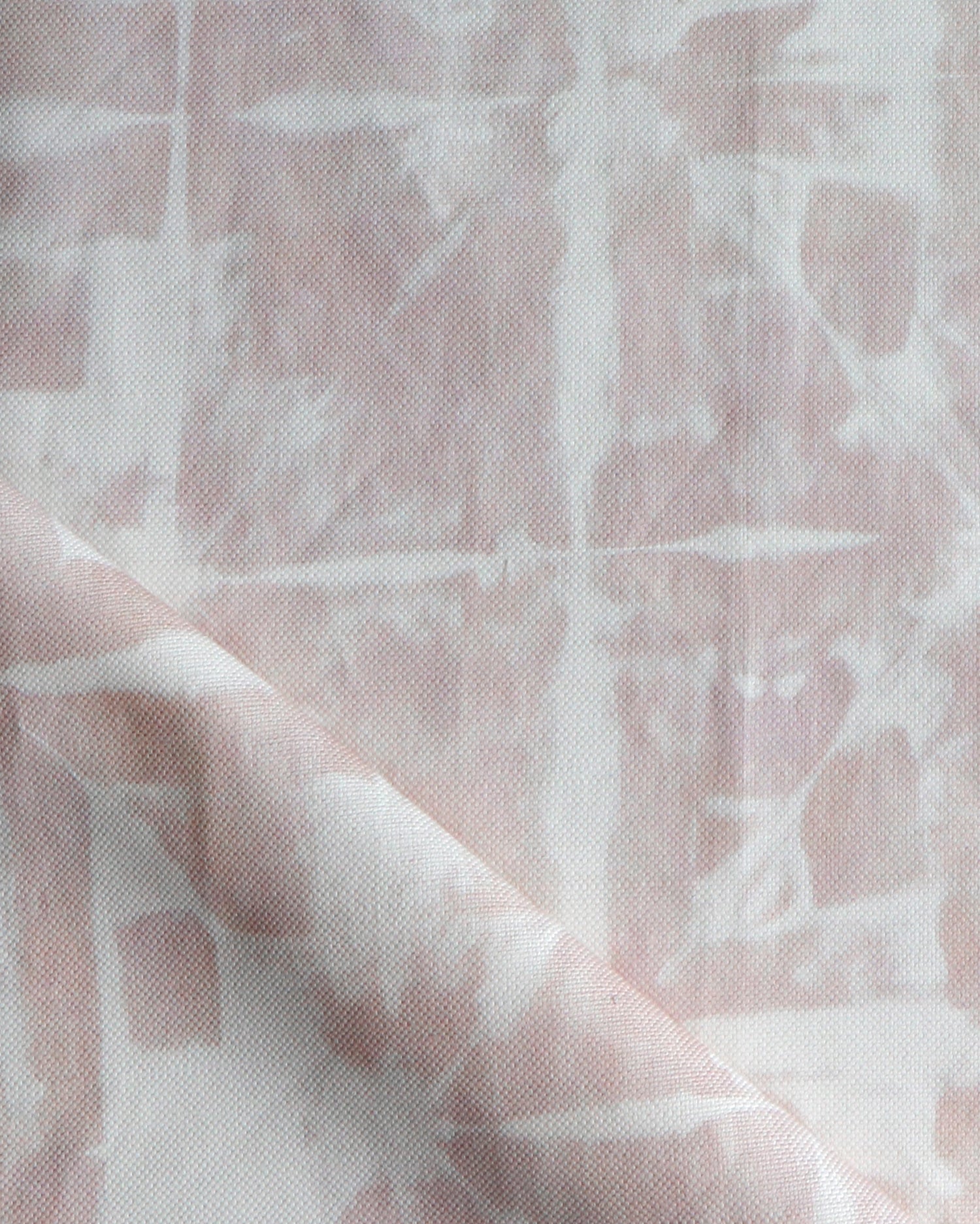 Detail of draped fabric in a watercolor dyed grid print in mottled white and pink.