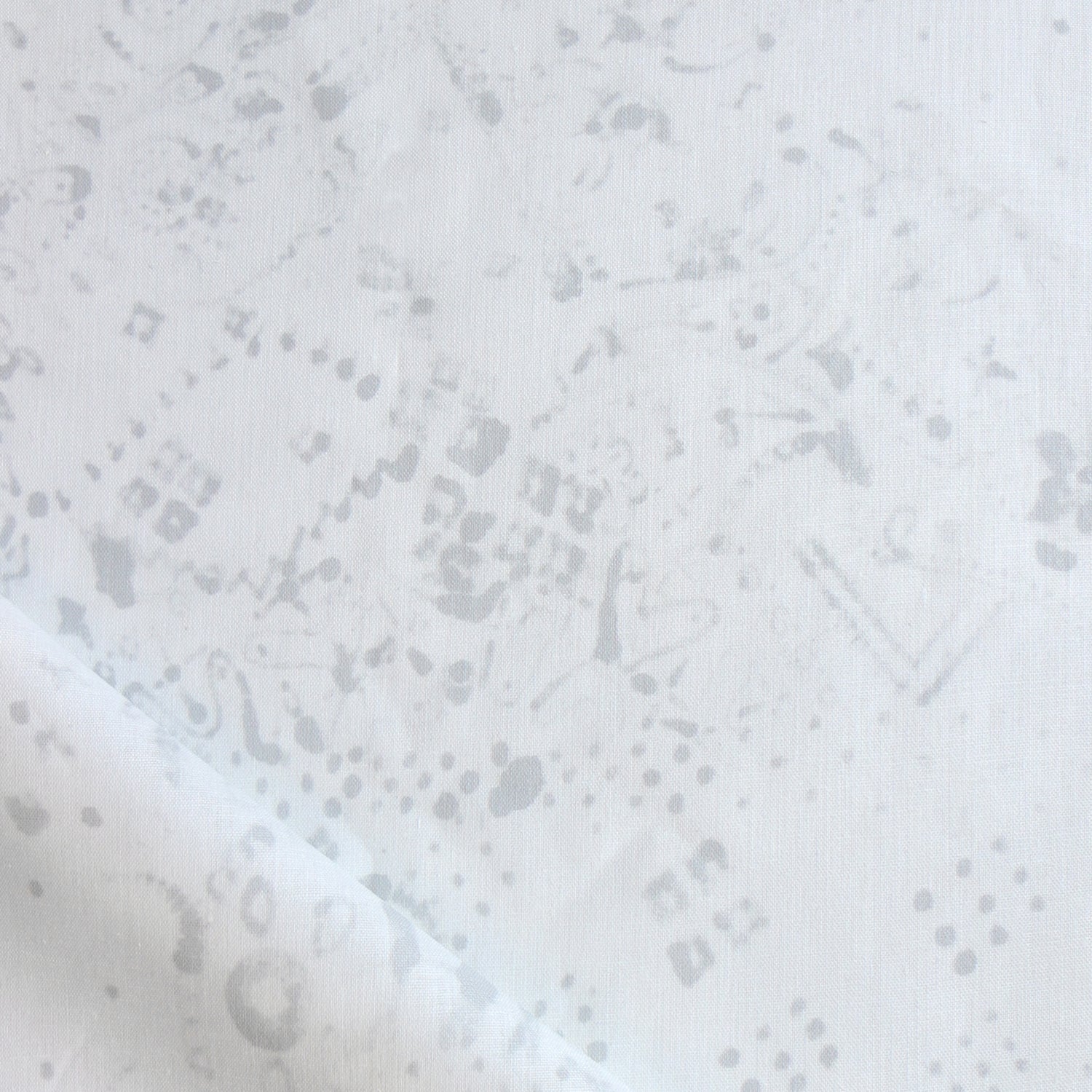 Detail of draped fabric in a painterly bandana print in light gray on a white field.