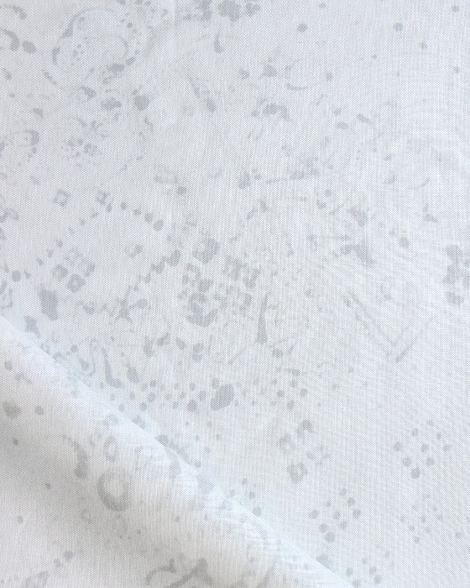Detail of draped fabric in a painterly bandana print in light gray on a white field.