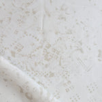 Detail of draped fabric in a painterly bandana print in beige on a cream field.