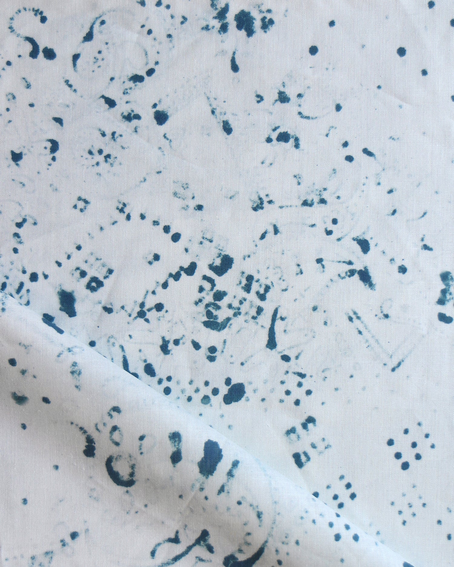 Detail of draped fabric in a painterly bandana print in navy on a white field.