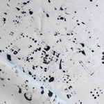 Detail of draped fabric in a painterly bandana print in black on a cream field.