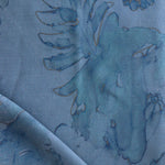 Detail of draped fabric in a painterly floral print in shades of navy and tan on a blue field.