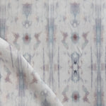 Detail of draped fabric in a painterly ikat print in turquoise, gray and tan.