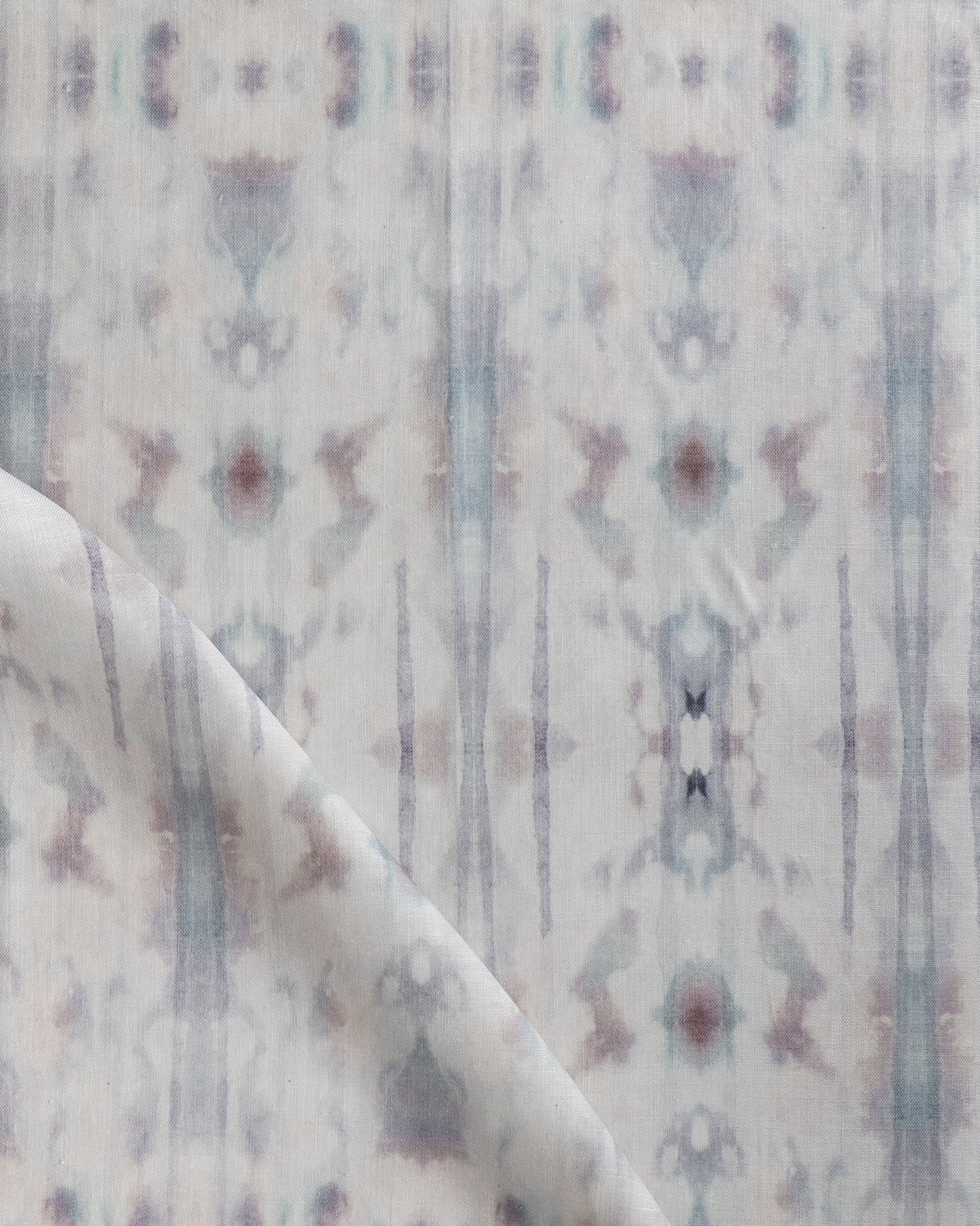 Detail of draped fabric in a painterly ikat print in turquoise, gray and tan.