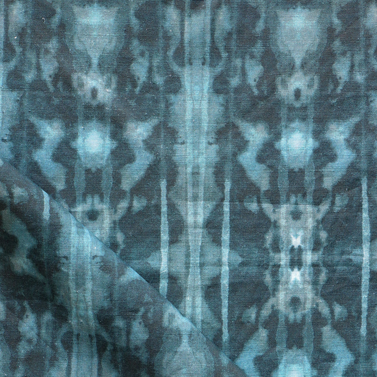 Detail of draped fabric in a painterly ikat print in turquoise and navy.