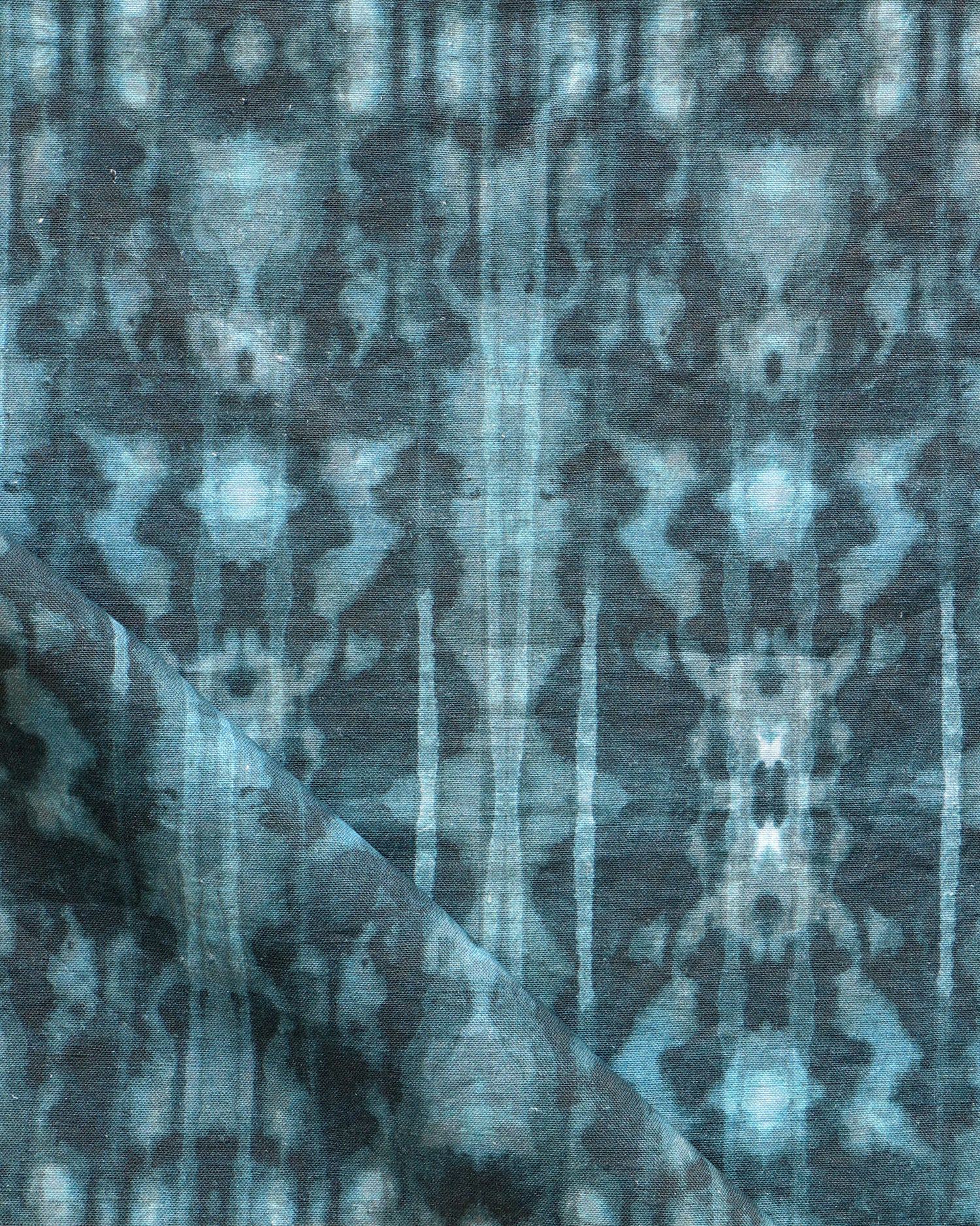 Detail of draped fabric in a painterly ikat print in turquoise and navy.