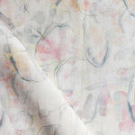 Detail of draped fabric in a watercolor painterly print in shades of pastel, green and cream.