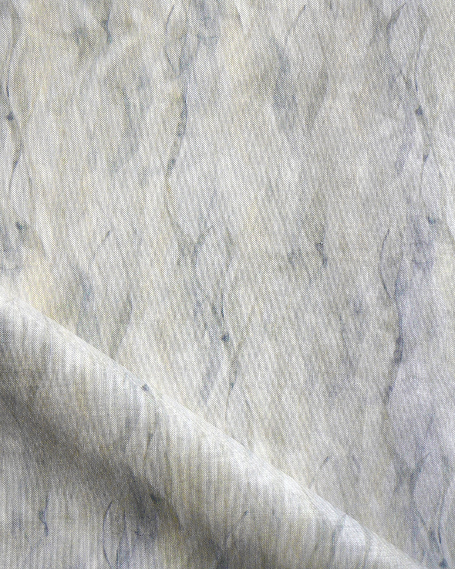 Draped fabric in a layered squiggle watercolor pattern in shades of grey and warn tan, 