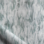 Draped fabric in a layered squiggle watercolor pattern in shades of muted teal. 