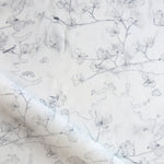 Draped fabric in a watercolor branch and floral pattern in soft grey on a white field