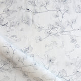 Draped fabric in a watercolor branch and floral pattern in soft grey on a white field
