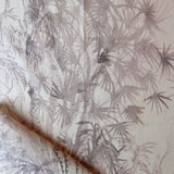 Detail of draped fabric in a painterly palm tree print in light pink on a cream field.