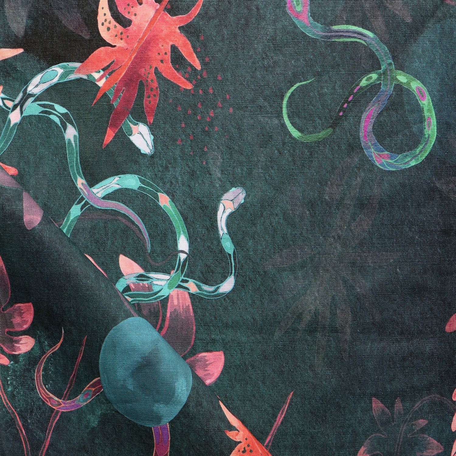 Detail of draped fabric in a playful leaf and snake print in pink, blue and green on a dark turquoise field.