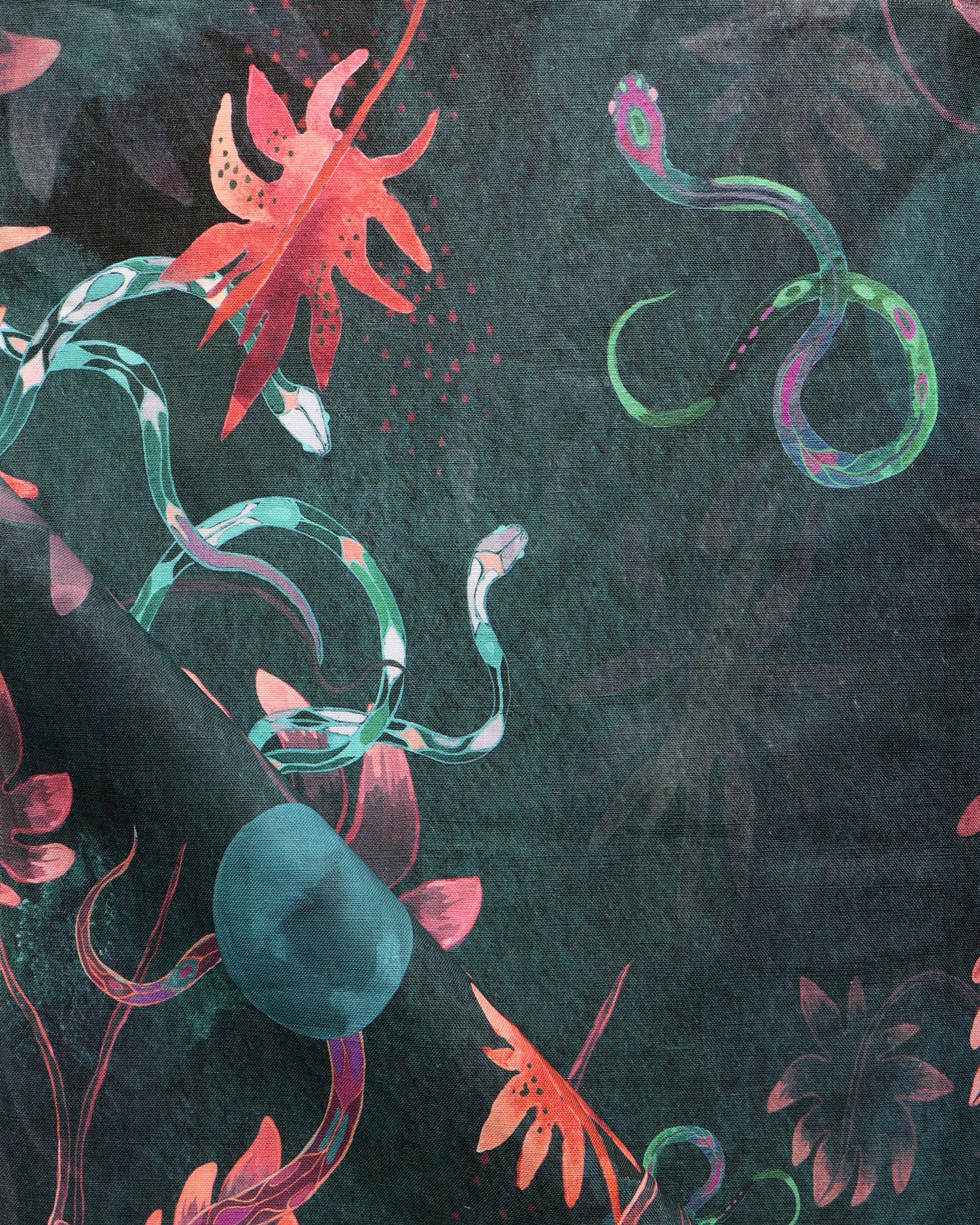 Detail of draped fabric in a playful leaf and snake print in pink, blue and green on a dark turquoise field.