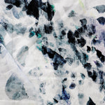 Detail of draped fabric in a watercolor paint blotch print in black, gray, blue and green on a white field.