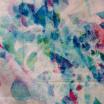 Detail of draped fabric in a watercolor paint blotch print in pink, green and turquoise on a white field.