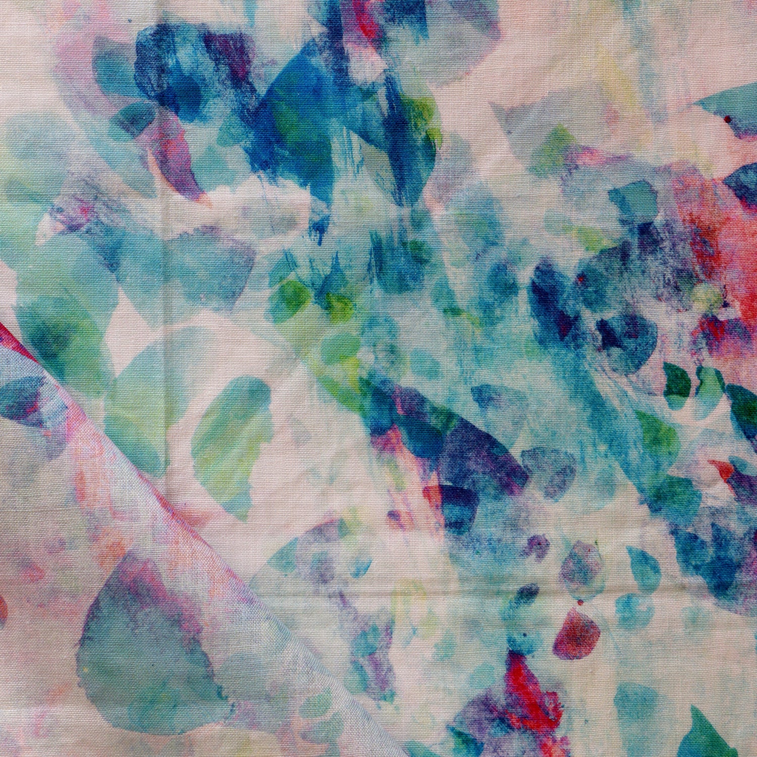 Detail of draped fabric in a watercolor paint blotch print in pink, green and turquoise on a white field.
