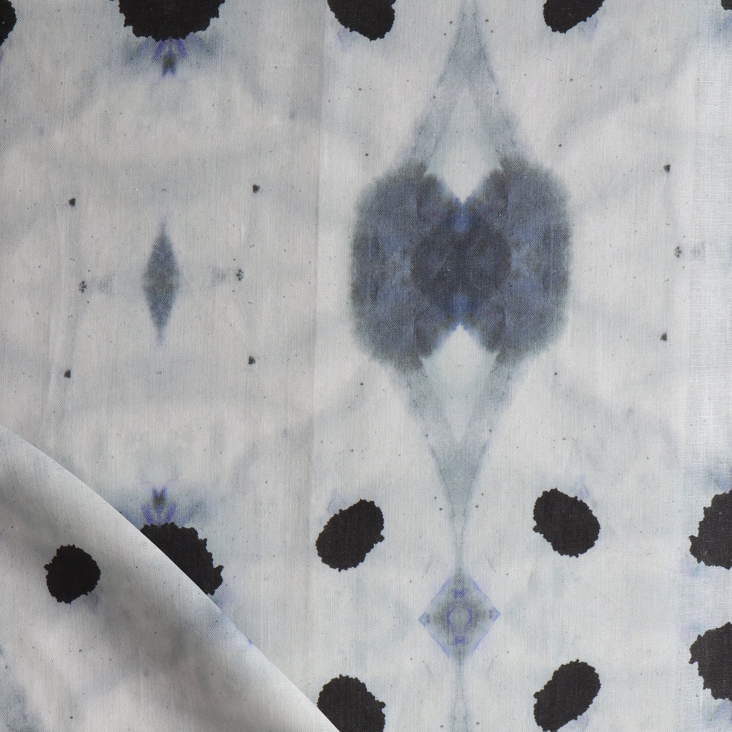 Detail of draped fabric in a watercolor ink blot print in shades of charcoal and black on a greige field.