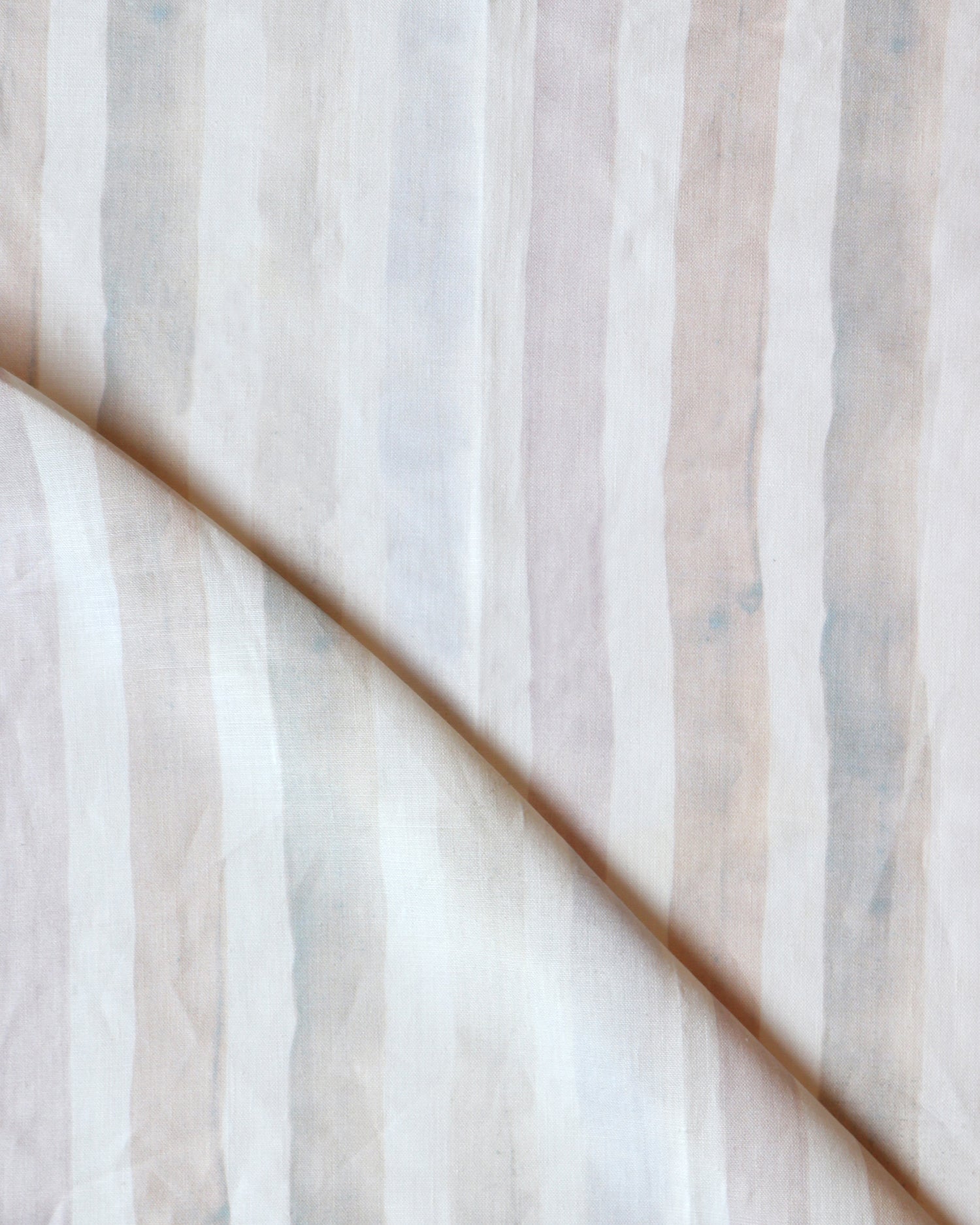 Detail of draped fabric in a painterly stripe print in shades of pink, gray and cream on a white field.