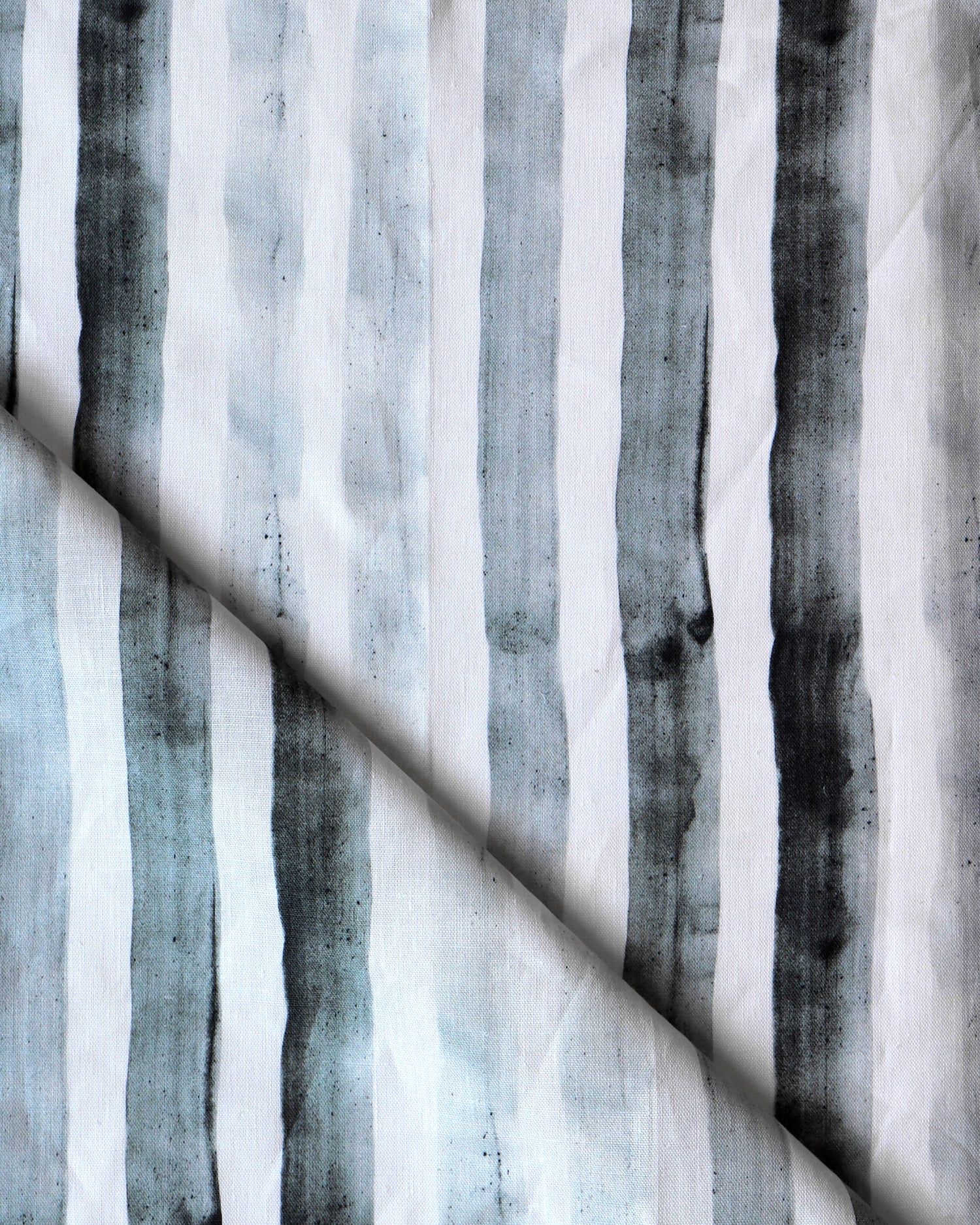 Detail of draped fabric in a painterly stripe print in shades of gray on a white field.