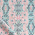 Detail of draped fabric in a painterly gometric stripe in gray, blue and green on a pink field.