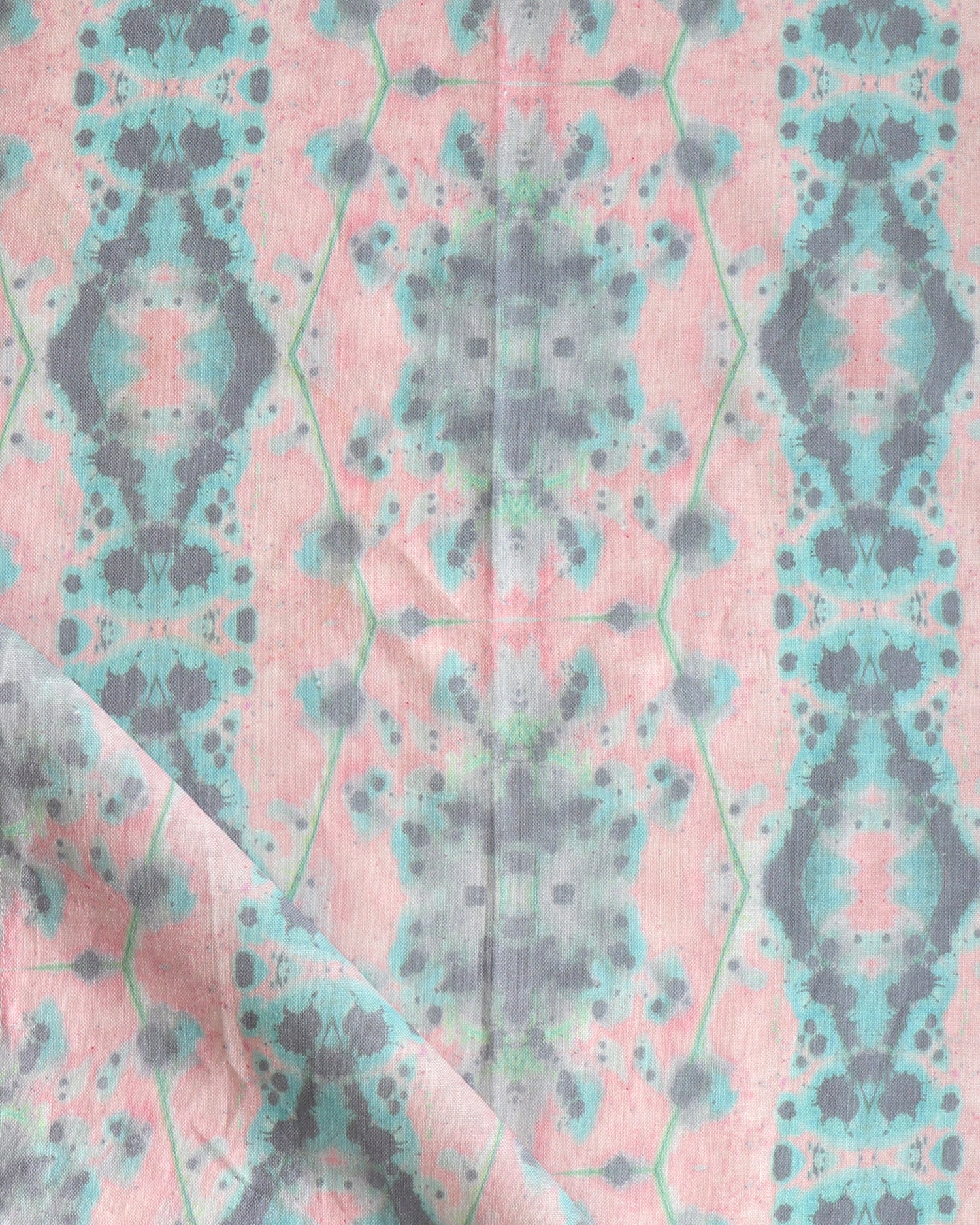 Detail of draped fabric in a painterly gometric stripe in gray, blue and green on a pink field.