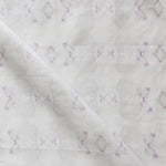 Detail of draped fabric in a striped ink blot print in shades of tan and purple on a cream field.