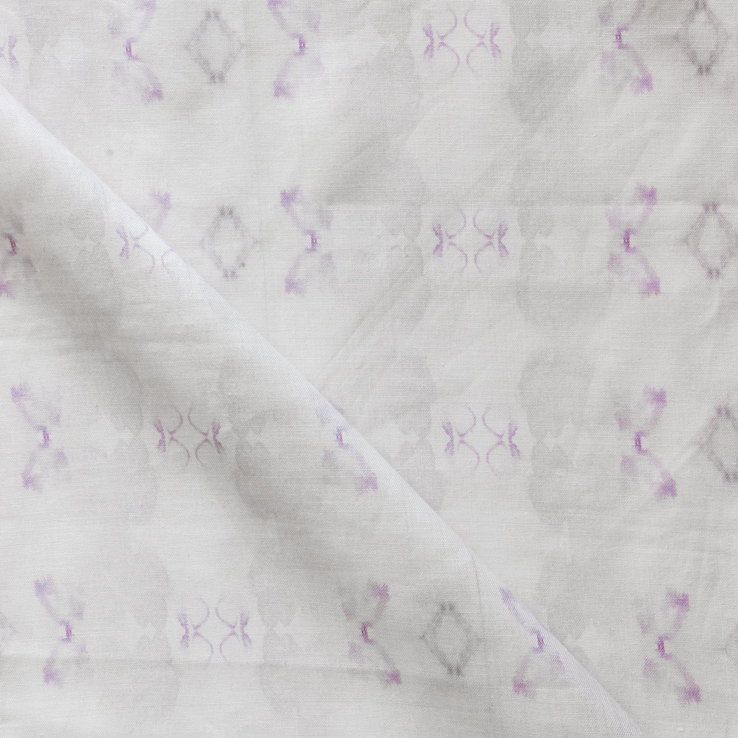 Detail of draped fabric in a striped ink blot print in shades of tan and purple on a cream field.