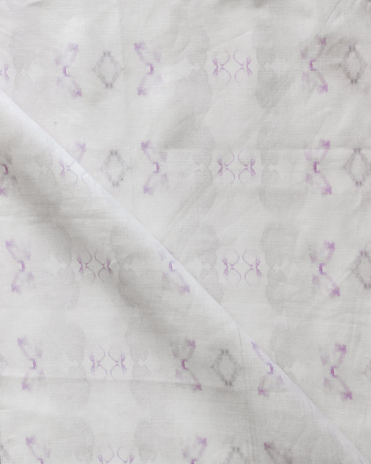 Detail of draped fabric in a striped ink blot print in shades of tan and purple on a cream field.